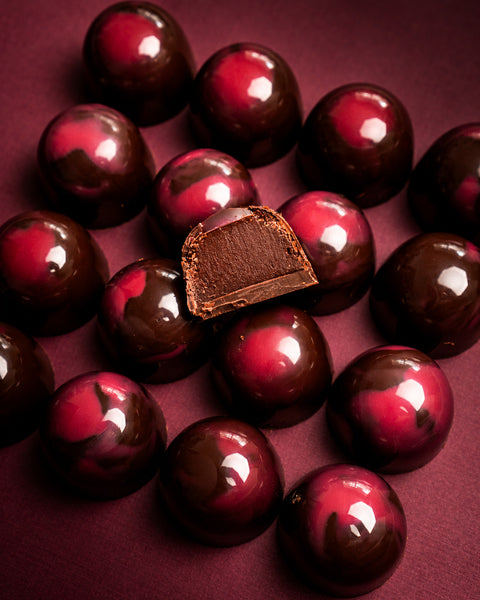 Cherry Amaretto dark chocolate ganache truffles, one cut open to show the ganache
